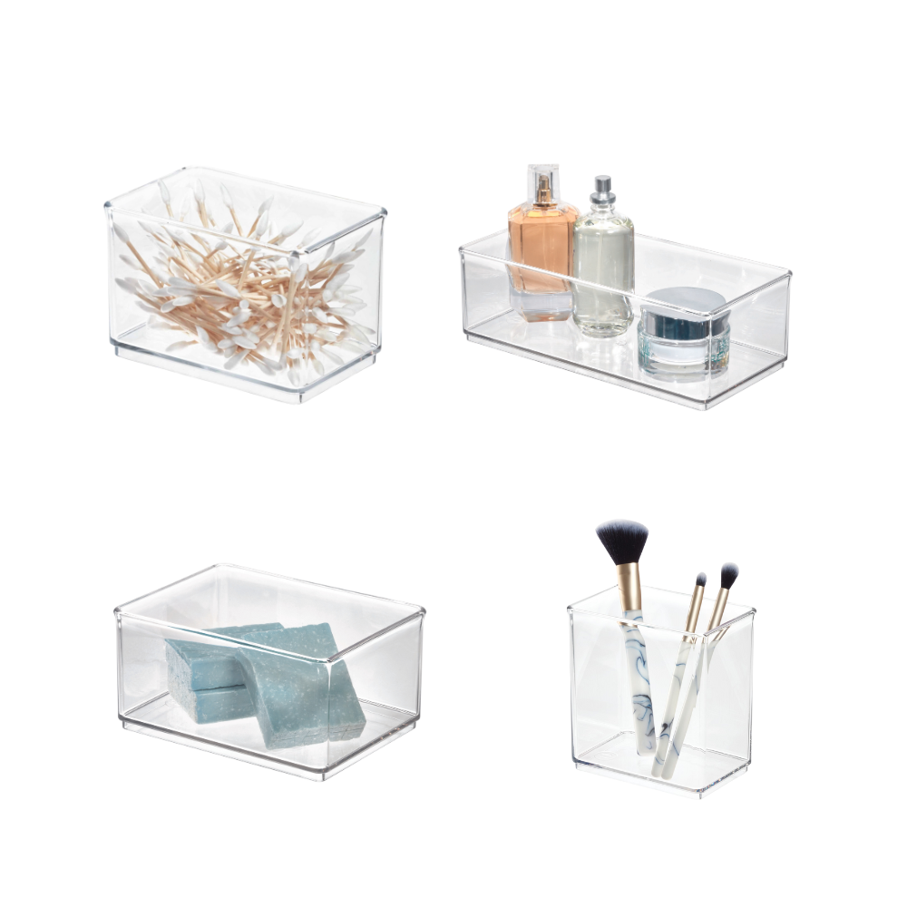 Vier transparente Kunststoffboxen mit Wattestäbchen, Parfum, Seifenstücken und Make-up-Pinseln.