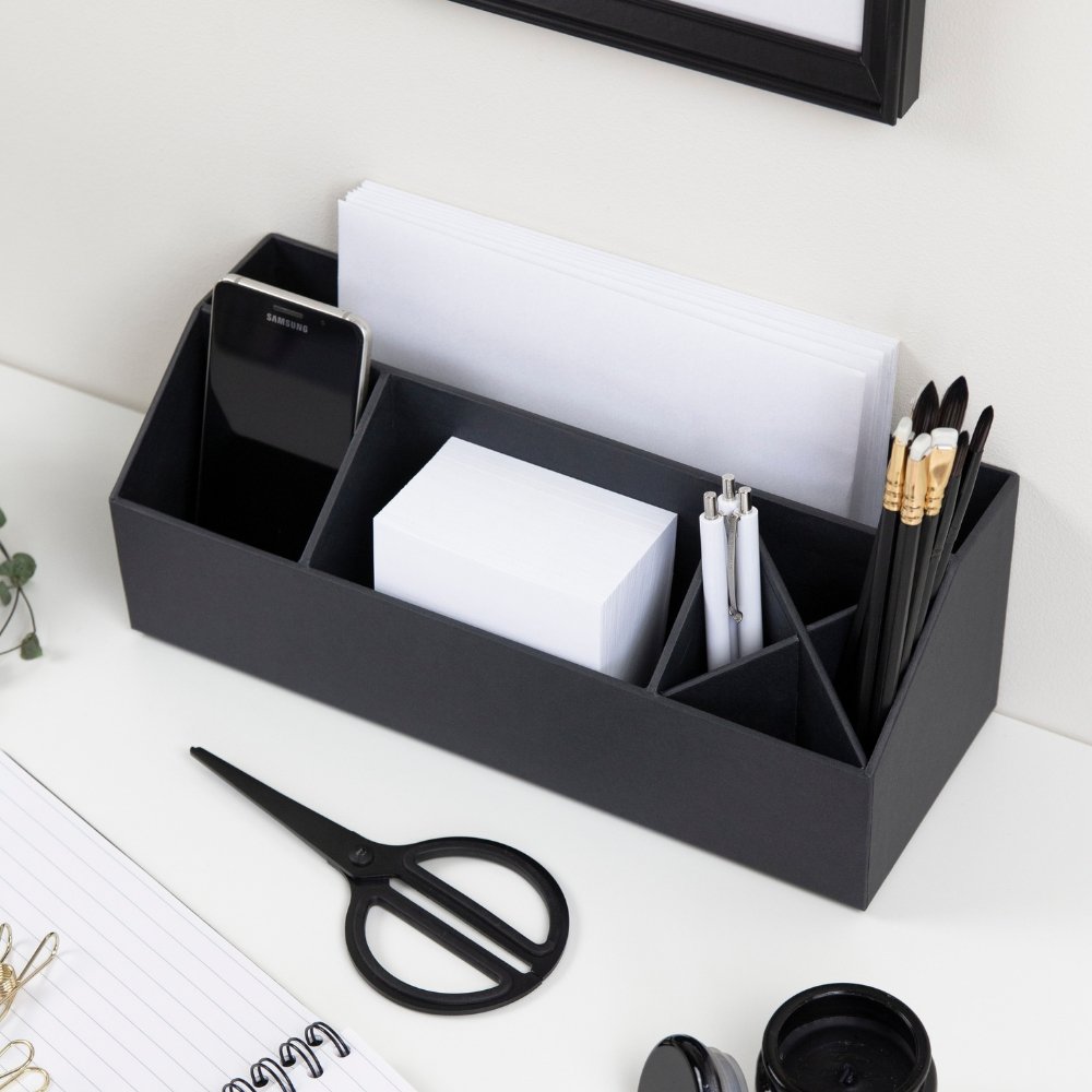 Schreibtisch-Organizer hält Smartphone, Papier, Stifte und Schere in Büro-Umgebung.
