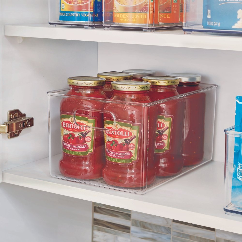 Gläser mit Tomatensoße stehen in transparentem Behälter auf einem Regal im Küchenschrank.