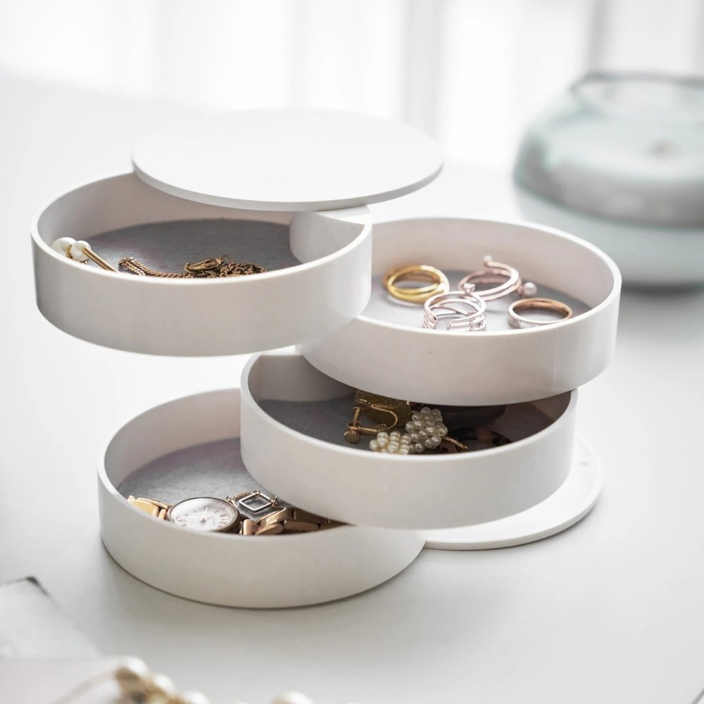 Schmuckorganizer mit schwenkbaren Fächern für Ringe, Uhren und Ohrringe, ausgestellt auf weißem Tisch.